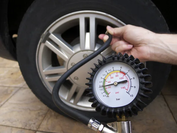 Driver and Equipment Checking Tire Pressure at Gas Station
